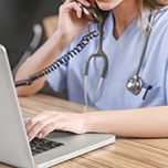 Sundhedsprofessionel sidder ved computeren og taler i telefon